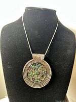 Full view of the necklace on black display showing chain and large pendant