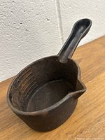 Side view of cast iron sauce pot showing the interior and spout.