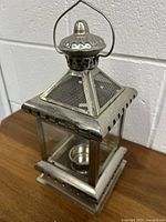 Front view of silver geometric metal tea light holder with mesh pyramid top and handle