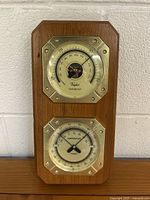 Full view of the wooden plaque with two octagonal metal-framed dials for barometer and temperature/hygrometer.