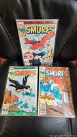 Three Smurfs comic books from 1982 lying on a black surface, showing cover art with Smurfs characters and issue numbers 1-3.
