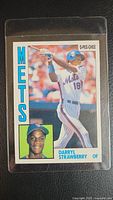 Front of Darryl Strawberry rookie baseball card showing batting pose and portrait in Mets uniform, card kept in a clear protective sleeve.