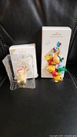 Photo of two Hallmark Keepsake Winnie the Pooh figures on black background, one still in plastic packaging with backing card, one outside packaging alongside box