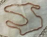 Full length of box link chain laid out flat on fabric background