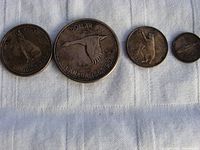 Four Canadian silver coins from 1867-1967 showing their obverse wildlife designs arranged on white fabric.