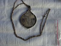 Pendant with mounted 1976 Montreal Olympiad $5 silver coin lying on a cloth background, showing full pendant and chain.