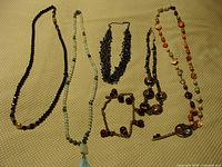 Overview of all necklaces and bracelet laid on a yellow textured surface