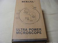 Photo of the BEBANG microscope packaging box showing the illustration of the microscope with magnification levels 4X, 10X, and 40X, and branding.