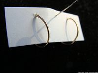 Two images of a pair of thin 10K gold hoop earrings attached to a white card, showing their circular shape and polished surface.