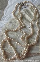 Full view of the double strand pearl necklace laid flat showing overall length and pearl condition.