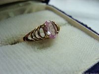 Close-up of the ring showcasing the pink rhinestone and gold band design in ring box.