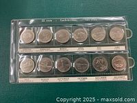 Front side of Confederation quarters showcasing various commemorative designs for each month, protected in plastic sleeve