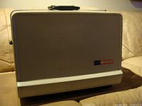 Closed case view with Singer branding visible, showcasing the projector's compact outer design.