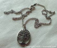 Photo showing the vintage sterling silver chain with the oval Tree of Life pendant laid out on fabric.