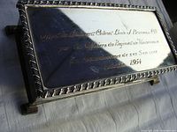 Close-up of the cigarette box lid showing the engraved military inscription in French dedicated to Lieutenant Colonel Louis J. Bruneau, dated October 1954.