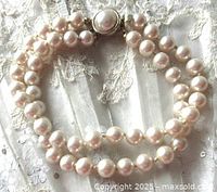 Double strand cream-colored pearl bracelet approximately 7.5 inches long with gold-tone pearl push-in clasp, laid flat on white lace background.