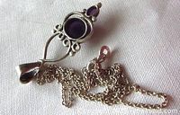Front view of pendant with two oval amethyst cabochons and detailed silver design, chain partially visible