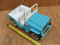 Side view of the blue and white metal jeep toy with a measuring tape showing length of about 10 inches, highlighting wear and paint condition.