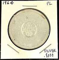 Photo of the reverse of the 1964 Canadian 1 Dollar silver coin showing the floral emblem and inscriptions including CANADA, DOLLAR, 1964, and CHARTER TO QUEBEC.