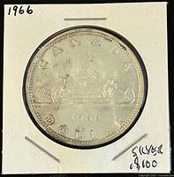Reverse side of the 1966 Canadian silver 1 dollar coin showing voyageur and Indigenous person in a canoe with inscriptions.