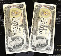 Two consecutive 1973 Canadian one dollar paper banknotes showing front side with serial numbers and Queen Elizabeth II portrait.