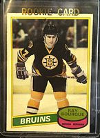 Front of 1980-1 O-Pee-Chee Ray Bourque rookie hockey card showing player in Bruins uniform, with 'ROOKIE CARD' text at top.