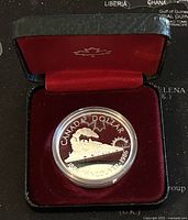 1986 Canadian Silver Proof Dollar coin in protective case inside a black display box with red velvet lining and maple leaf emblem.