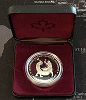 Silver proof dollar coin displayed in a red velvet-lined black case with maple leaf emblem.