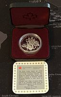 Silver proof coin in maroon velvet-lined case with coin and information card visible