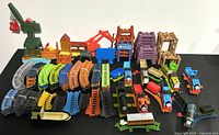 Overview of Thomas the Train and Friends toy trains with numerous track pieces laid out on white background, including cranes and various accessories