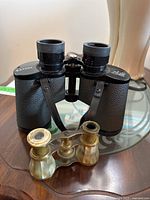 Eaton 8x40 field binoculars and antique mother of pearl brass opera glasses on glass table