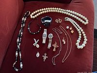 All items on red fabric, showing watches, necklaces, pendants, and earrings in lot