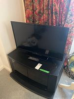 Full view of LG 32-inch TV placed on a black MDF entertainment stand with two glass doors and two shelves