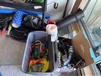 Photo showing baskets with assorted exercise bands, weights, and therapy pads, a black rolled-up yoga mat, and a blue textured foam roller with protruding nodules for muscle massage.