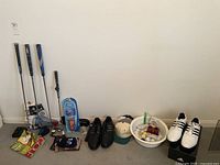 Four golf clubs, insoles box, two pairs of shoes, two caps, bowl of balls and practice weights
