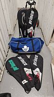 Five Prince tennis racquets with covers and blue Toronto Maple Leafs gym bag arranged in storage area