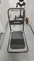 Front view of the Husky collapsible cart with handle upright, showing brand logo and platform surface.