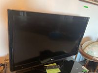 Full front view of LG 42" television with remote on stand.