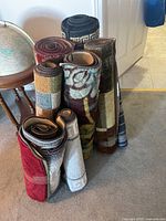 Rolled floor mats grouped standing upright showing different patterns and colors.