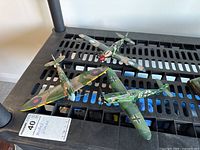 Three plastic WWII-era model airplanes displayed together, showing camouflage and markings; missing landing wheels noted