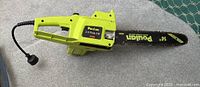 Full side view of the green Poulan electric chainsaw with attached 14-inch guide bar and chain, electric cord with plug visible.