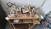 Full display of religious items on wooden table including crucifixes, wall art, charms, and small framed pictures.