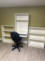 Photo of the two white shelves positioned on either side of the desk along with a black office chair in front.
