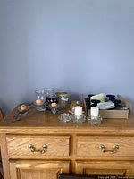 Lot of various candle holders on wooden surface including glass and metal holders with original box