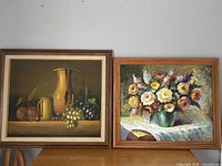 Pair of original framed paintings. Left: still life with fruit and yellow pitcher. Right: floral bouquet in green vase.