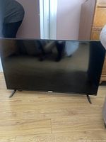 Photo of Philips 36 inch flat screen TV on floor with black frame and stand feet