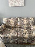 Front view of the retro floral patterned loveseat showing the full front profile and fabric design.