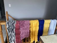 Seven handmade afghans draped over stair railing, showing colors and textures