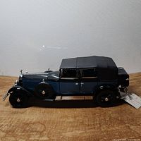 Side profile of the model showing the black fabric roof, blue body, black fenders, running boards, and front side spare tire.