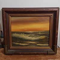 Frontal view of the framed oil painting showing ocean waves, sunset sky, and birds. Frame exhibits wear and tear.